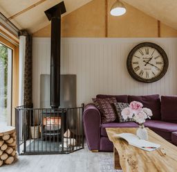 A living room with a purple sofa and a fireplace at Lodge 19 in Corfe Castle