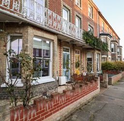A row of brick terrace houses with small front gardens and decorative railings at Elkhorn in Southwold