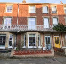 A row of brick townhouses with bay windows and a blue door with a sign reading Elkhorn in Southwold