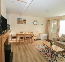 A living room with a sofa and coffee table and a dining table with chairs at The Bolthole in Dartmouth