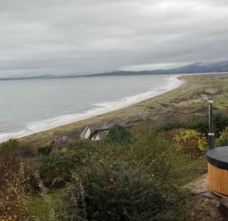 View of the beach and sea with a hot tub in the foreground at Sibrwd Y Mor in Harlech
