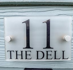 A house number sign with 11 and the name The Dell on a textured light blue wall at 11 The Dell in Mundesley