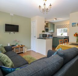 A living room with a television and dining area at 14 The Dell Mundesley