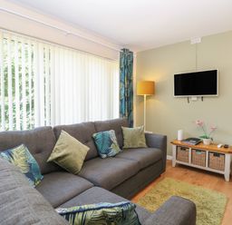 A living room with a sofa and television at 14 The Dell Mundesley