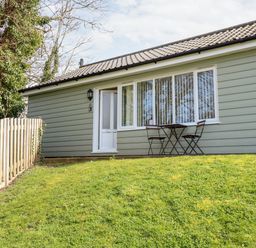 Exterior of a single-story house with a small table and two chairs on the grass at 15 The Dell in Mundesley