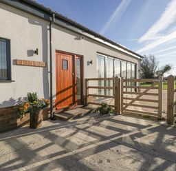 Entrance of a house with a wooden door flower pots wooden gate and a window at Bilsham Meadows in Aust