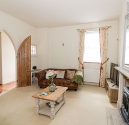 A living room with a brown leather sofa a wooden coffee table a fireplace and a wooden TV stand at 4 The Old Council House Shipston-On-Stour