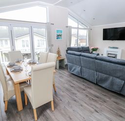 A living room with a dining area and television at Dono's Lodge, Stepaside near Kilgetty, Heritage Park