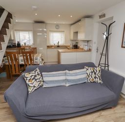 A living room with a sofa and kitchen area at 22 Longstone Park Beadnell