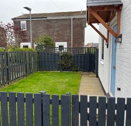 A garden with grass and a wooden fence at 22 Longstone Park Beadnell