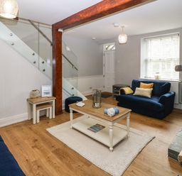 A living room with blue sofas a wooden coffee table and a staircase at Belle View in Llaniestyn near Abersoch