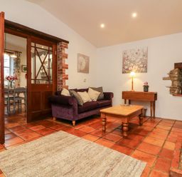 A living room with a purple sofa wooden coffee table and stained glass window at The Shippen in Gooseham near Kilkhampton