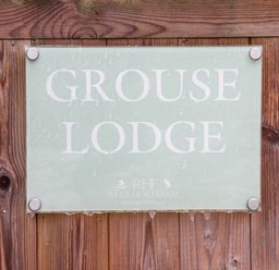 A sign reading Grouse Lodge mounted on wooden boards at Riggs Head Farm
