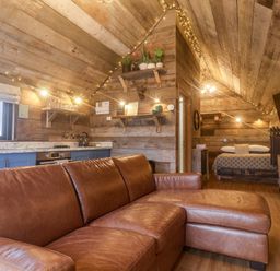 A wooden room with a brown leather sofa blue kitchen cabinets and a bed at Foxes Den in Seamer North Yorkshire