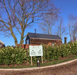 A driveway with gravel and green shrubs beside a signpost pointing to Sunset Retreat and Foxes Den at Foxes Den in Seamer North Yorkshire