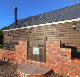 Exterior view of a wooden building with a brick wall and a small gate with a sign that says Foxes Den in Seamer North Yorkshire