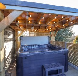 An outdoor hot tub under a wooden pergola with string lights on the ceiling at Sunset Retreat in Seamer North Yorkshire