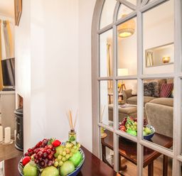 A living room with a sofa and pillows reflected in a mirror and a bowl of fruit on a table at Quarrier's Rest in Swanage