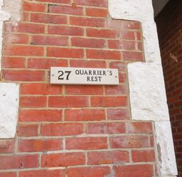 A brick wall with a white sign showing number 27 and the name Quarrier's Rest