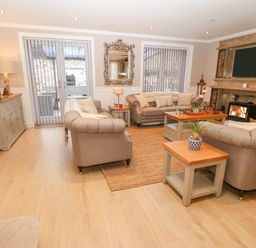 A living room with three sofas a coffee table a side table a cabinet a wall clock a fireplace and a mirror at Ty Bains in Llanberis
