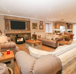 A living room with sofas a coffee table a fireplace and an open kitchen at Ty Bains in Llanberis