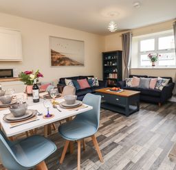 A dining table set with dishes and glasses next to a living area with sofas and a coffee table at Lonnon Cottage in Alnmouth