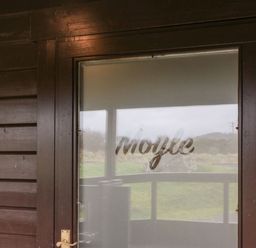 A wooden door with frosted glass and the word Moyle on the glass at Moyle Lodge in Dalbeattie