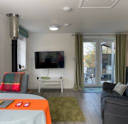 A living room with a TV on the wall a sofa a small table and glass doors leading outside at The View in Cardinham