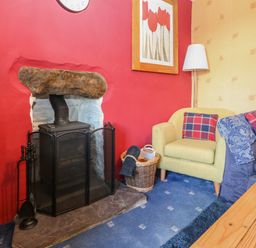 A living room with a wood stove fireplace armchair sofa and coffee table at Bod Feurig in Penygroes