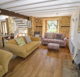 A living room with two sofas armchair fireplace and wooden floor at The Paddock in New Yatt near Witney