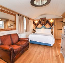 A bedroom with a brown leather sofa a bed wooden floor and a kitchen counter at The White Princess in Bolton Percy near Tadcaster