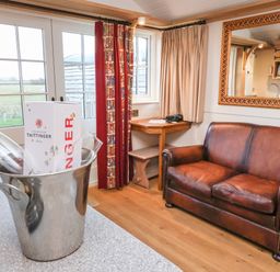 A living area with a brown leather sofa a small wooden table with a chair and a mirror on the wall at The White Princess in Bolton Percy near Tadcaster