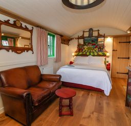 A bedroom with a leather sofa a bed with a colorful headboard and a wooden door at Folklore Bolton Percy near Tadcaster