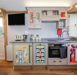 A kitchen with a stove oven sink and cabinets with colorful artwork at The Studio in Bolton Percy near Tadcaster