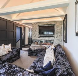 A living room with black velvet sofas and a wall-mounted TV above a modern fireplace at Whisk Away Cottage Greystoke near Troutbeck Near Penrith