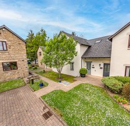 A courtyard with stone and white houses grass trees and shrubs at Whisk Away Cottage in Greystoke near Troutbeck Near Penrith