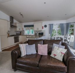 A living room with kitchen area and dining table at Seacroft in Stepaside near Kilgetty