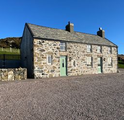 A stone cottage with green doors and windows in a rural area at Pennant Igyn in Mynytho near Abersoch
