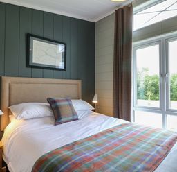 A bedroom with a double bed a framed picture bedside tables with lamps and a window with curtains at Holly Lodge in Winthorpe near Newark-On-Trent