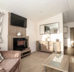 A living room with a sofa a wall mounted television fireplace cabinet coffee table and sideboard at Orion in Felmoor Park