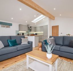 A living room with two sofas a coffee table and a kitchen in the background at 7 Valley View in Lanreath