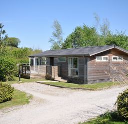A wooden house with a deck and garden space at 7 Valley View in Lanreath