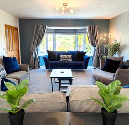 A living room with sofas cushions plants and a window at Sanderson House in Cleator Moor