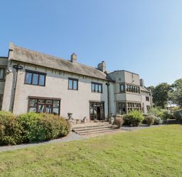 The exterior of a multi-story house with windows bushes and a lawn at Highcliffe Manor in Flamborough