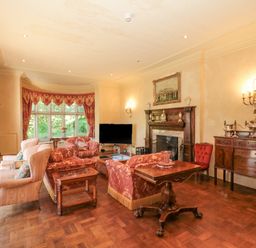 A living room with wooden furniture a fireplace large windows and red patterned curtains at Highcliffe Manor in Flamborough