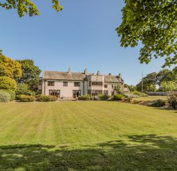 A large house with multiple windows and a tiled roof surrounded by a lawn and trees at Highcliffe Manor in Flamborough