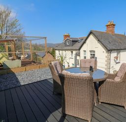An outdoor deck with a round glass table and four wicker chairs with cushions at The Outlook in Minehead