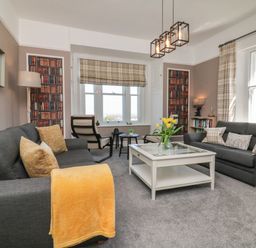 A living room with two dark sofas a white coffee table yellow flowers and two armchairs at The Outlook in Minehead