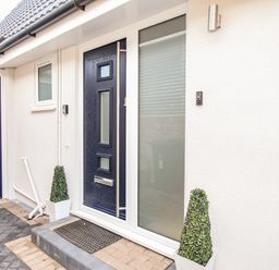 A front door with glass panels flanked by two potted plants and a garage door at The White House in Weymouth