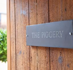 A sign on a wooden door reading The Piggery at The Piggery in Ledbury near Welland